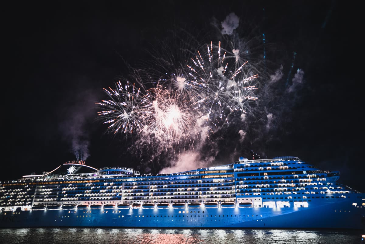 Illuminated cruise ship at night with fireworks